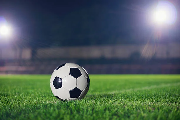Soccer ball on grass under stadium lights at night